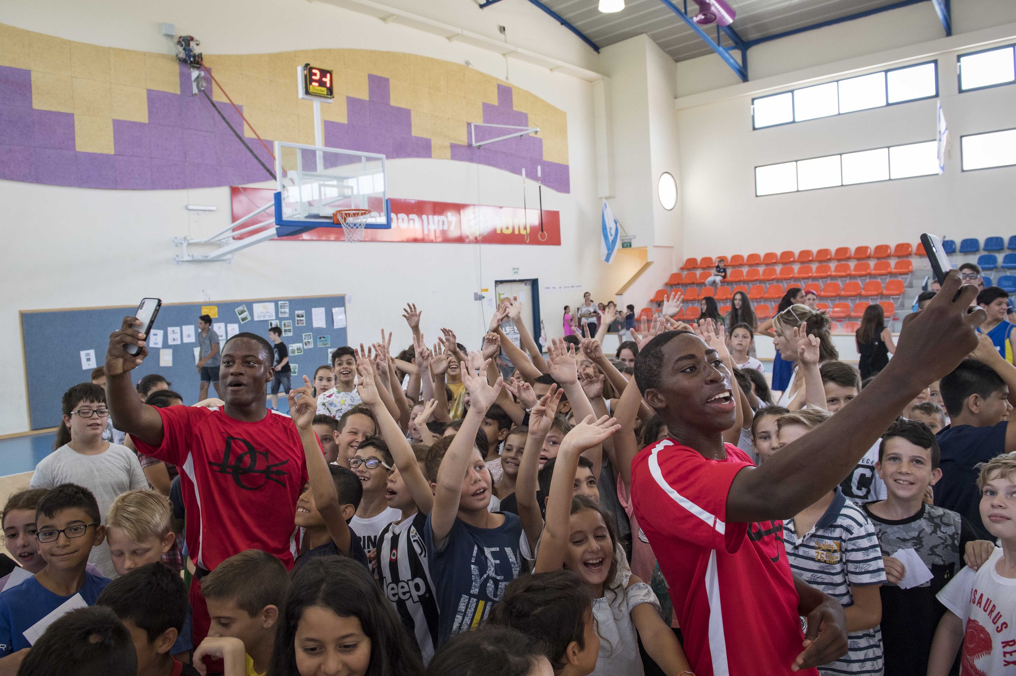Kinder vor einem Basketballfeld mit Handys stehend während eines Basketballcamps.