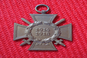 Ein rotes Tuch mit einer silbernen Medaille, die einen Kranz und eine Inschrift trägt, in der Mitte des Tuchs.