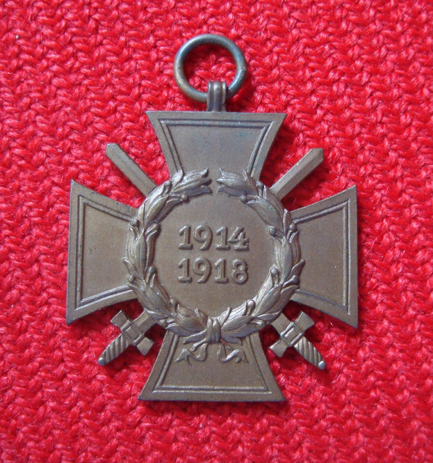 Ein rotes Tuch mit einer silbernen Medaille, die einen Kranz und eine Inschrift trägt, in der Mitte des Tuchs.