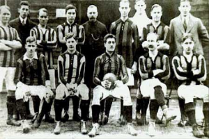 Ein Schwarz-Weiß-Foto einer Fußballmannschaft, einige stehen, einige sitzen, vor einer Wand, mit dem Text "Ballymena Football Club" unten.