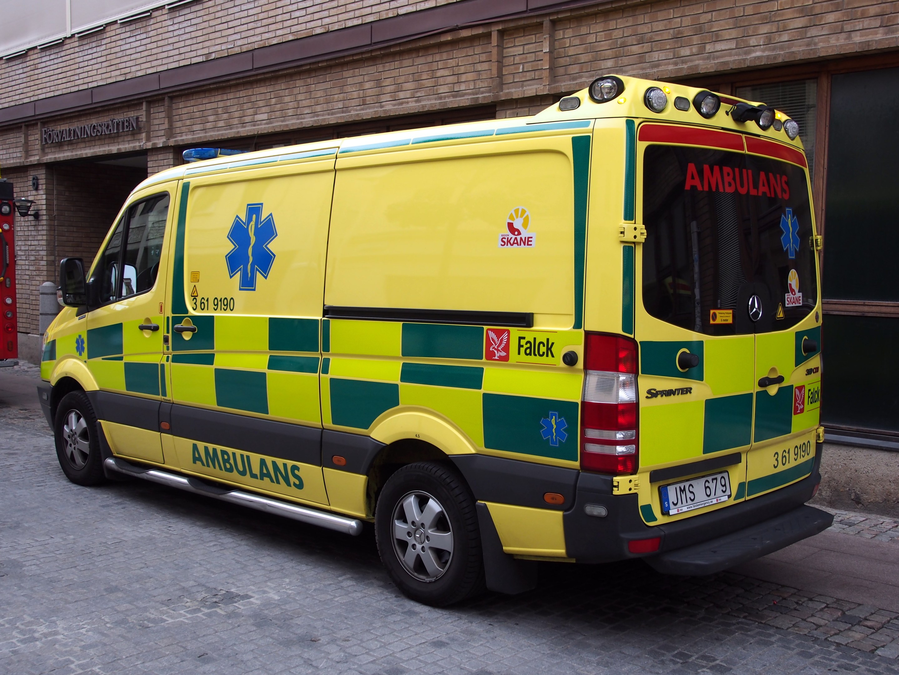 Ambulanz vor einem Backsteingebäude mit Text geparkt, mit einem Feuerlöscher auf der linken Seite.