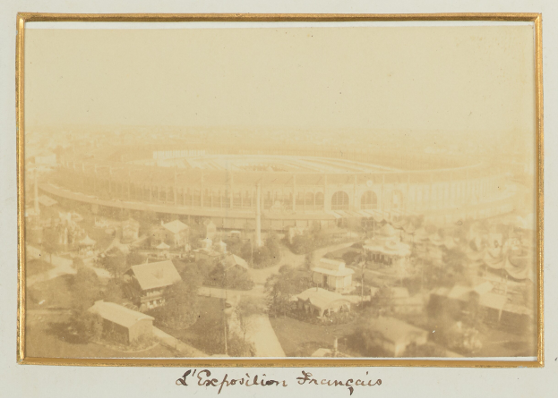 Altes Schwarz-Weiß-Foto eines Stadions inmitten einer Stadt, umgeben von mehrstöckigen Gebäuden, vereinzelten Bäumen und Strommasten, mit undeutlicher Schrift am unteren Rand.