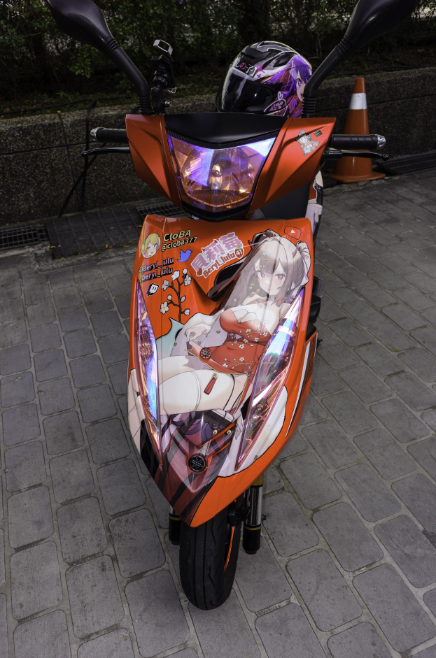 Ein oranges E-Scooter mit Helm daneben, neben einer Verkehrsinsel, einer Wand und Bäumen im Hintergrund.