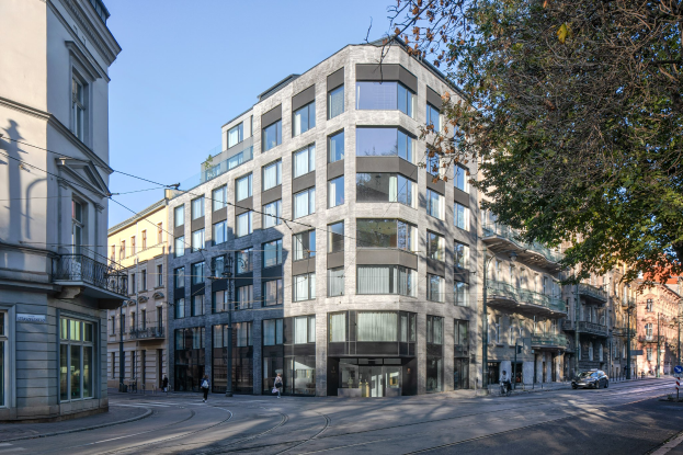 Großes Bürogebäude mit zahlreichen Fenstern, umgeben von Straßeninfrastruktur, Fahrzeugen, Fußgängern, Bäumen und einem bewölkten Himmel als neuer Firmensitz.