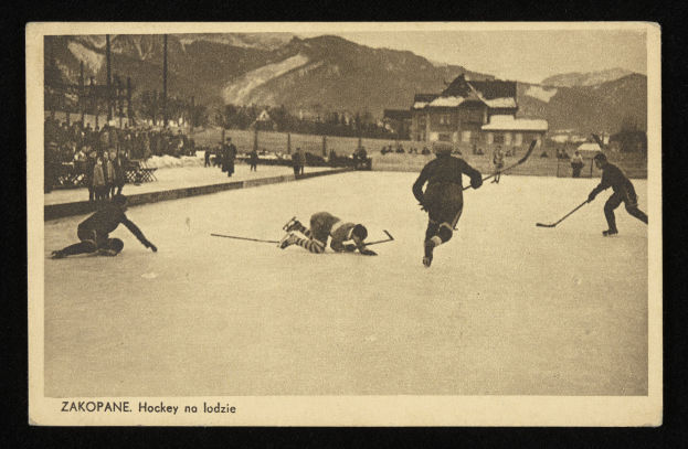Schwarz-weißes Foto von Menschen, die Hockey auf einem Eisplatz spielen, mit Gebäuden, Bäumen, Pfählen und Bergen im Hintergrund, einschließlich Text unten.