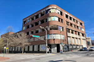 Altes Backsteingebäude mit der Aufschrift "Fortythia Medical Center" an einer Straßenecke, jetzt abgerissen, mit umgebender Straßeninfrastruktur und Fahrzeugen.