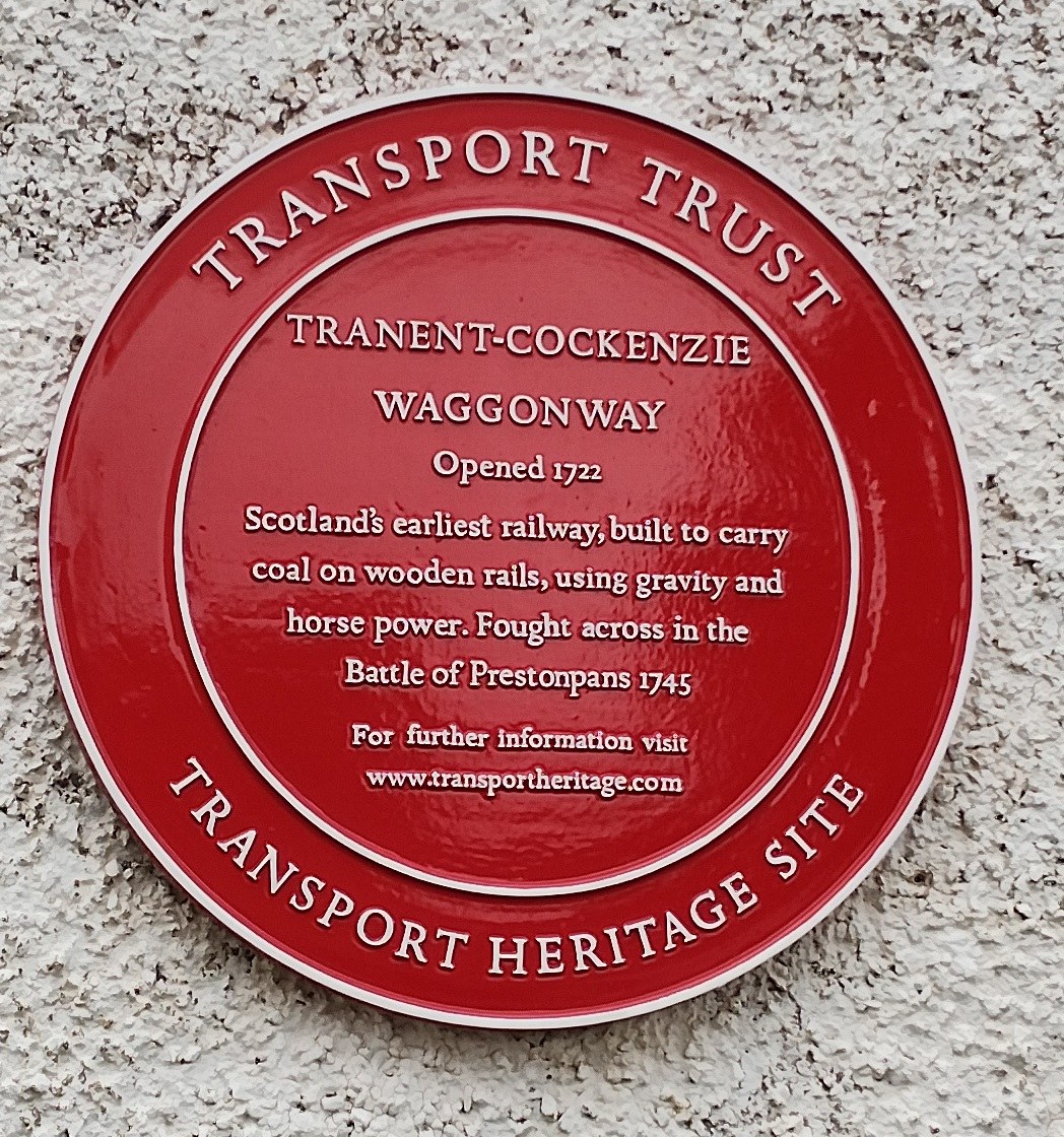 Ein roter runder Schild an einer Gebäudeseite mit der Aufschrift "Transport Trust".