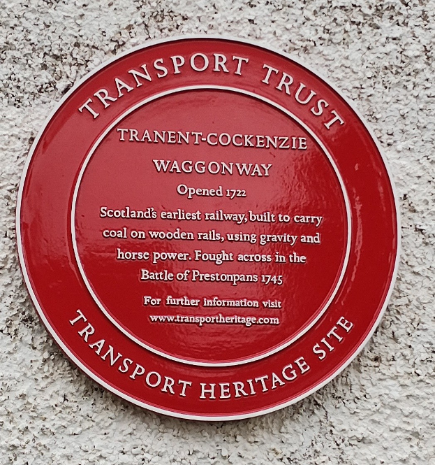 Ein roter runder Schild an einer Gebäudeseite mit der Aufschrift "Transport Trust".
