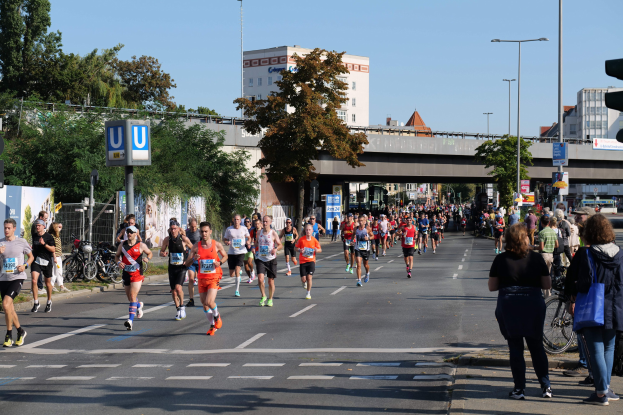 Gruppe von Menschen, die bei einem Marathon auf einer von Bäumen gesäumten Straße laufen