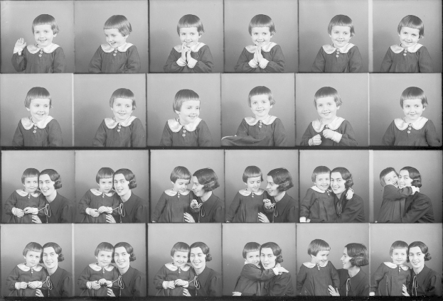 Schwarzes und weißes Foto einer Gruppe von Kindern mit einer Frau in der Mitte, die ein Baby hält und beide warm aneinander lächeln.