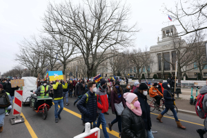 Ein großer Protestmarsch mit Menschen, die Schilder halten und Fahrräder auf einer Straße in Washington, D.C. am 21. Januar 2020 fahren, mit Bäumen, Schildern und einem klaren blauen Himmel im Hintergrund.