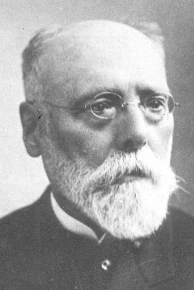 Schwarzes und weißes Porträt eines bärtigen Mannes in einem schwarzen Kleid und Brille mit ernstem Gesichtsausdruck, wahrscheinlich ein Soziologe.