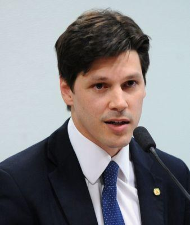 Ein Mann im Anzug und mit Krawatte spricht in ein Mikrofon an einem Rednerpult, wahrscheinlich zur Genehmigung eines Gesetzes durch die Regierung.