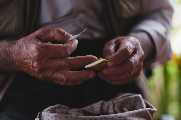 Alter Mann hält ein Blatt Papier in der Hand und sieht besorgt aus, mit unscharfem Hintergrund.