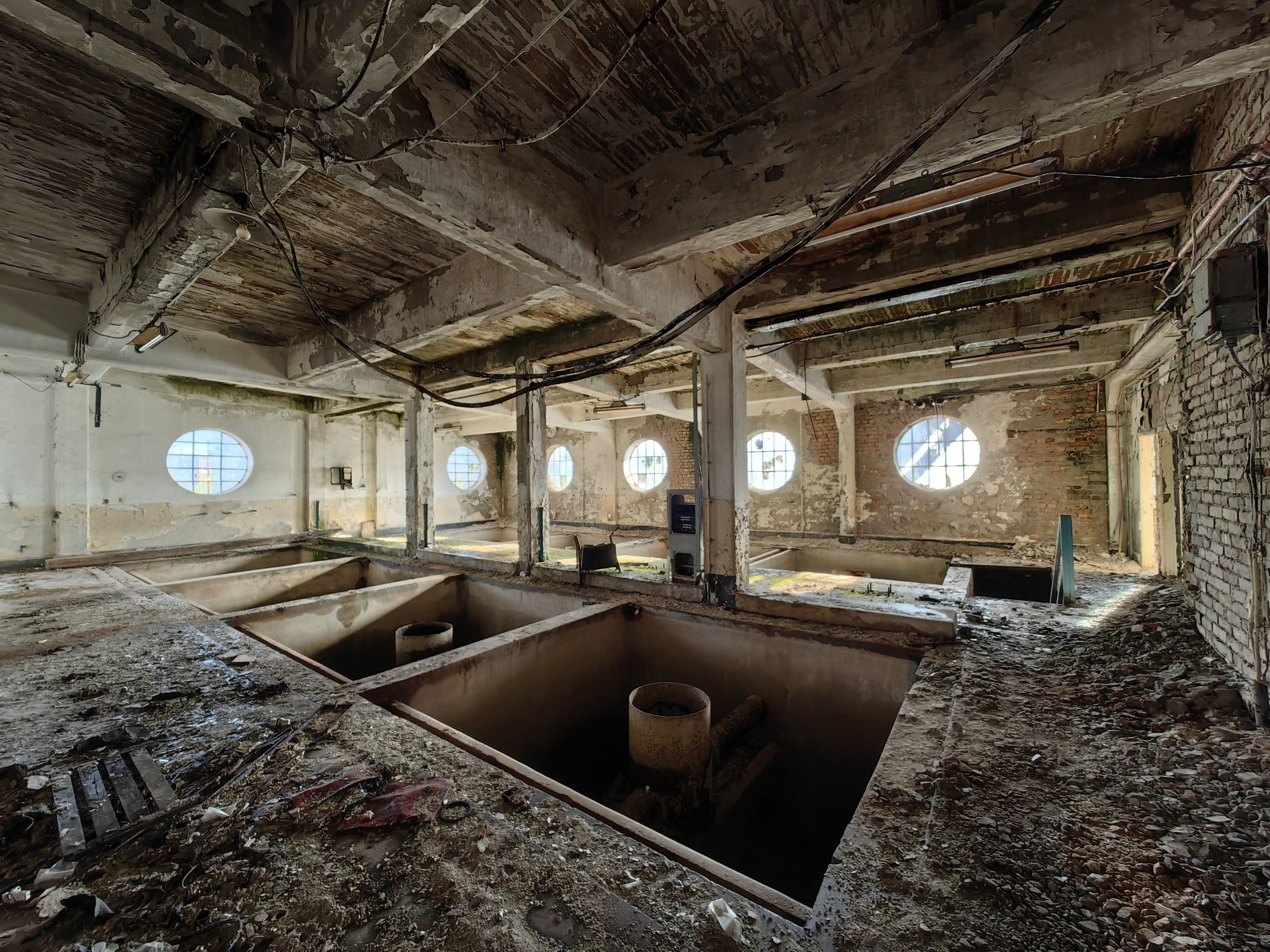 Verlassenes Gebäude-Innenraum im Chernobyl-Ausschlussgebiet mit verstreuten Trümmern, freiliegenden Wänden, Decke und strukturellen Elementen.