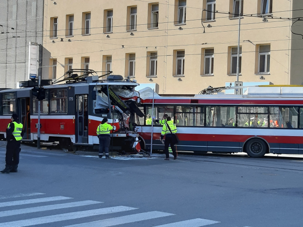 Rote und weiße Tram ist auf der Seite der Straße mit ein paar Menschen in der Nähe und einem Gebäude im Hintergrund zum Crash gekommen.