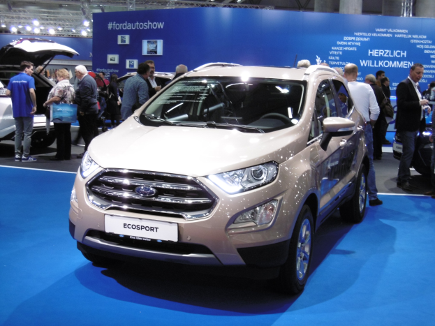 Ein weißer Ford Ecosport auf der Internationalen Automobil-Ausstellung in Frankfurt, umgeben von Menschen, mit Deckenbeleuchtung und einem Textschild im Hintergrund.