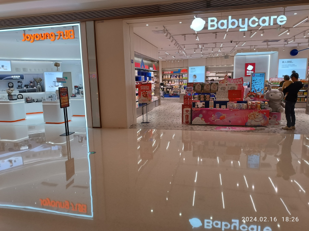 Ein Babyladen in einem Einkaufszentrum, mit Menschen, die Artikel wie Spielzeuge und Regale mit Produkten durchstöbern, unter Deckenlampen im Mall of Asia.