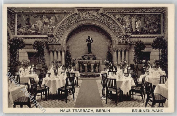 Ein altes Schwarz-Weiß-Foto eines Restaurants in Berlin mit Tischen, Stühlen, Blumenvasen, einer Statue, Skulpturen und Pflanzen an den Wänden, mit Text unten.