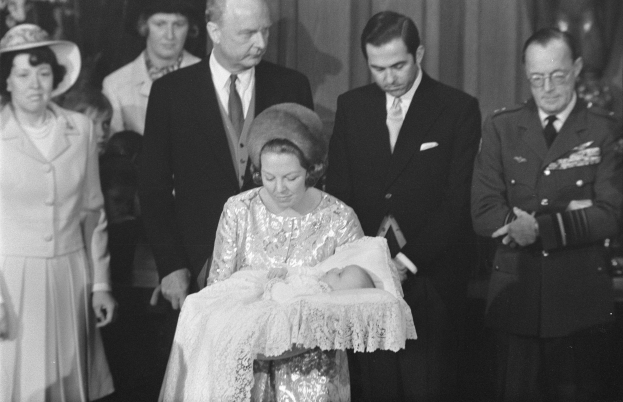 Königin Elizabeth II. wiegt ihren neugeborenen Sohn Prinz Philip in den Armen, während Prinz Philip, Herzog von Edinburgh, neben ihr in einem Anzug und Krawatte steht, vor einem Vorhanghintergrund.