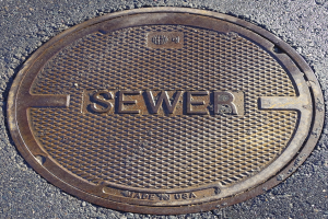 Metallschachtdeckel auf der Straße mit dem Wort "Kanal" geprägt