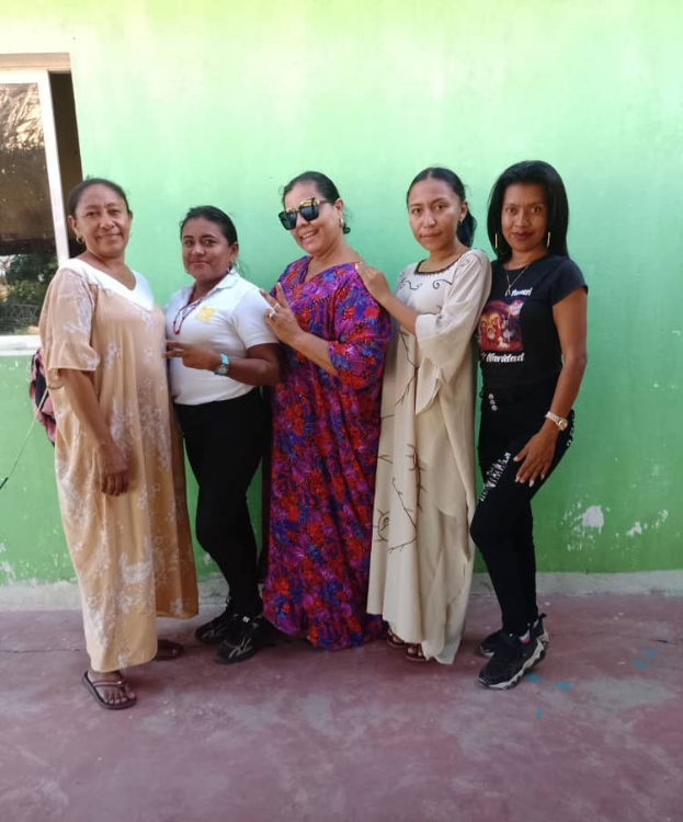 Frauengruppe vor einer grünen Wand mit einem Fenster auf der linken Seite bei einer Internationalen Frauentagsveranstaltung.