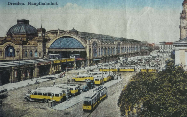 Ein Vintage-Postkarte zeigt den Dresdner Hauptbahnhof in Dresden, Deutschland, mit einer belebten StraßenSzene, Fußgängern, Bäumen, Gebäuden und einem bewölkten Himmel.