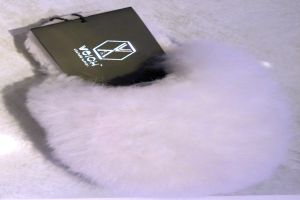 Ein weißer Pelzbeutel mit einer schwarzen Markierung, aus Schafsfell hergestellt, auf einer weißen Oberfläche.